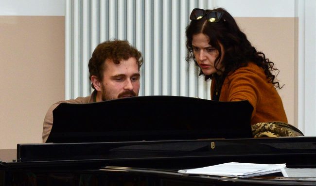 Ein Mann und eine Frau sitzen an einem Klavier und betrachten die Tasten.