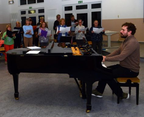 Eine Gruppe von Frauen singt gemeinsam, einige halten Notenblätter in den Händen.