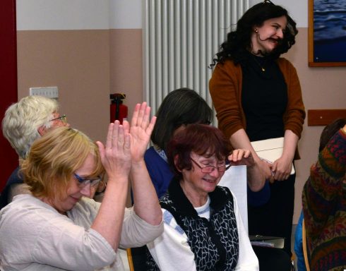 Eine Gruppe von Frauen singt gemeinsam, einige halten Notenblätter in den Händen.