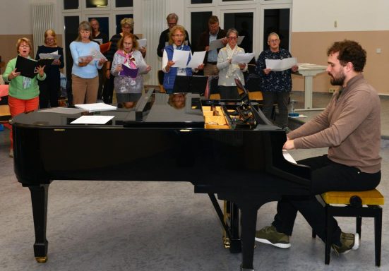 Eine Gruppe von Frauen singt gemeinsam, einige halten Notenblätter in den Händen.